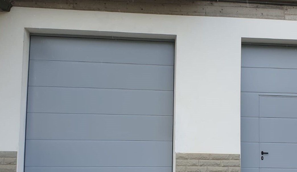 Porte sezionali grigie con porta pedonale per box a Torino