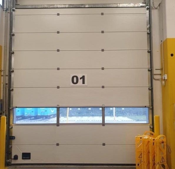 Portone sezionale industriale con finestratura su baia di carico a Torino